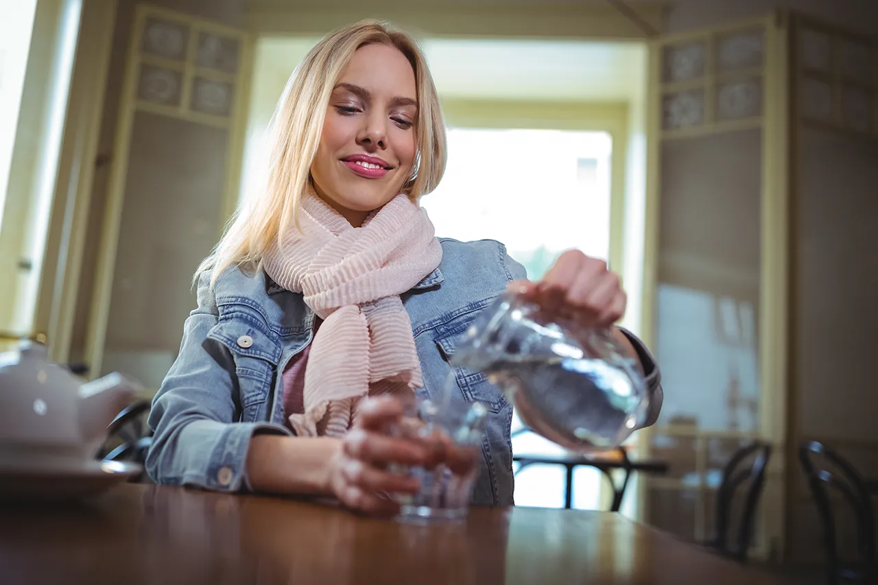 giovane ragazza che versa acqua filtrata e purificata